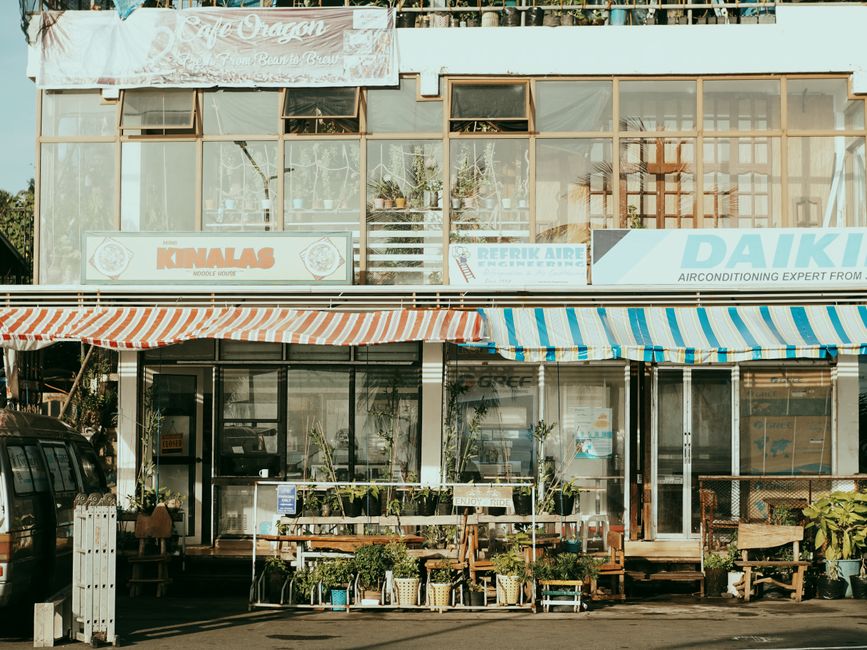 Charming street scene featuring local shops with colorful striped awnings and outdoor plants.