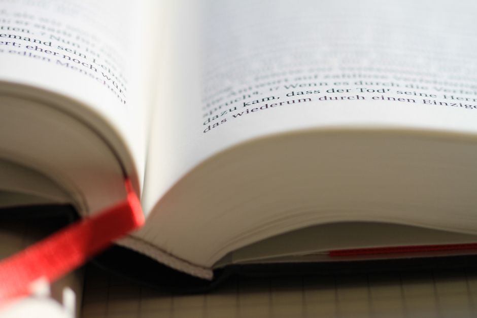 Open book with focus on page and red bookmark for reading and study.